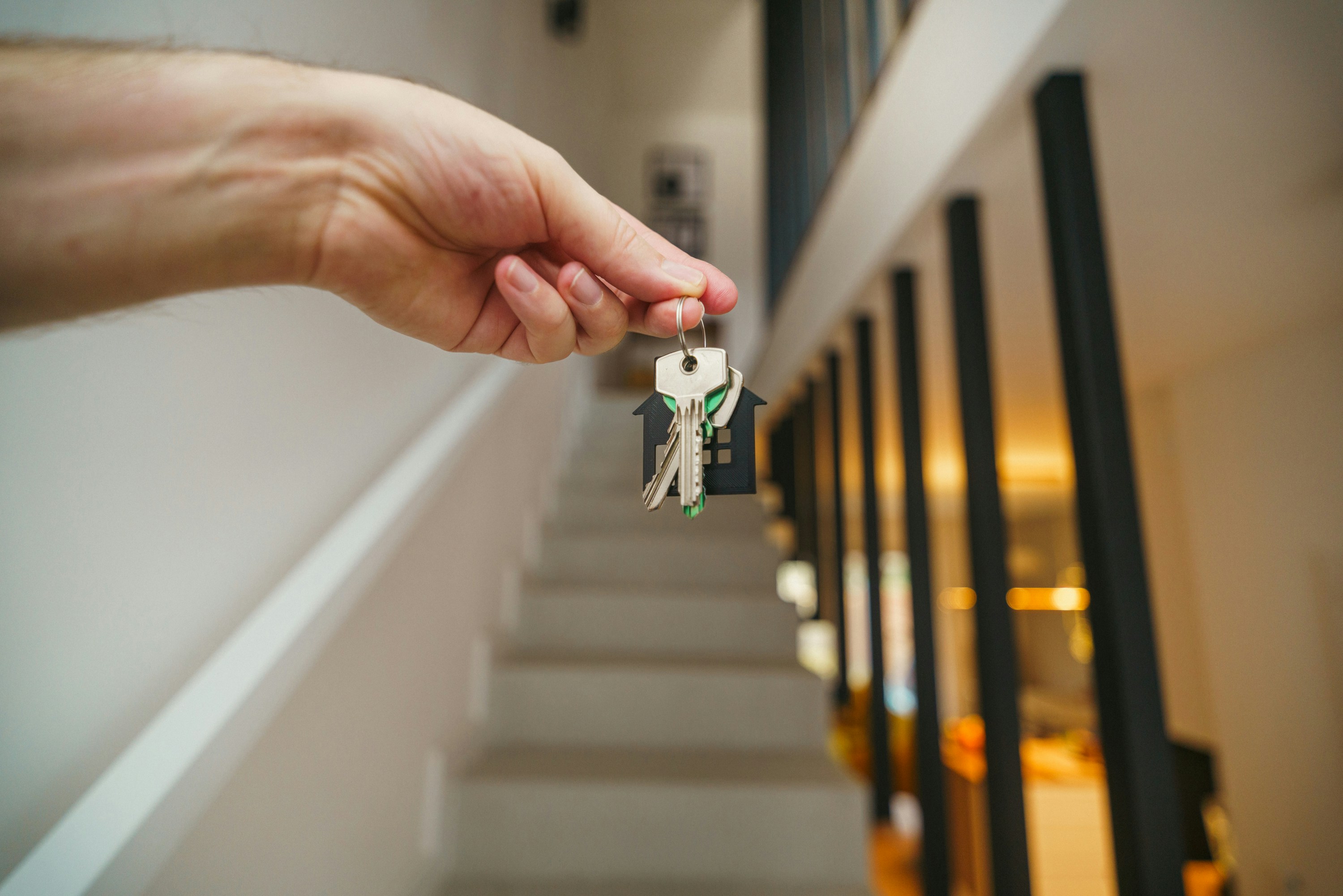 First time home buyer holding a set of keys with stairway behind