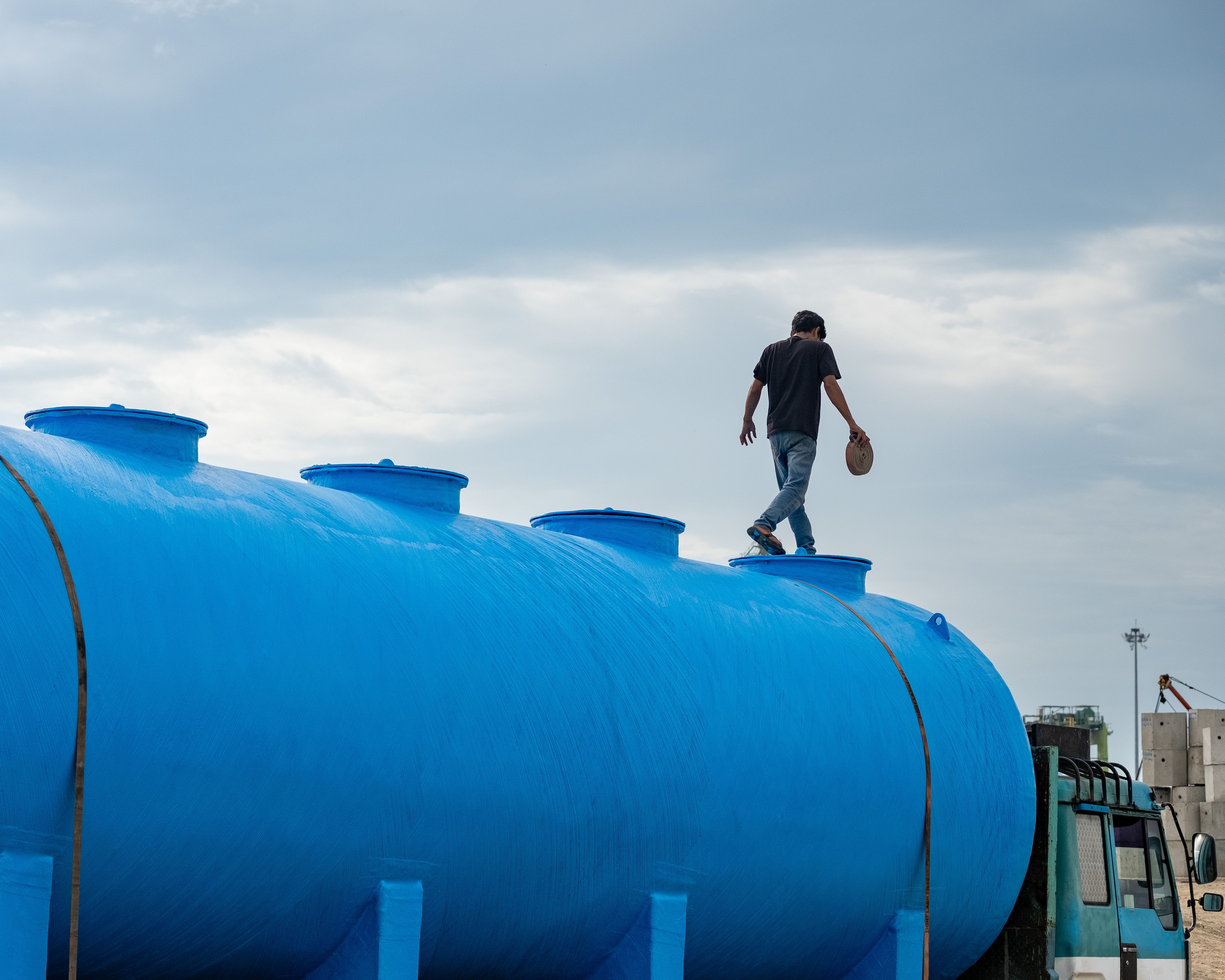 Man standing on top of blue septic tank